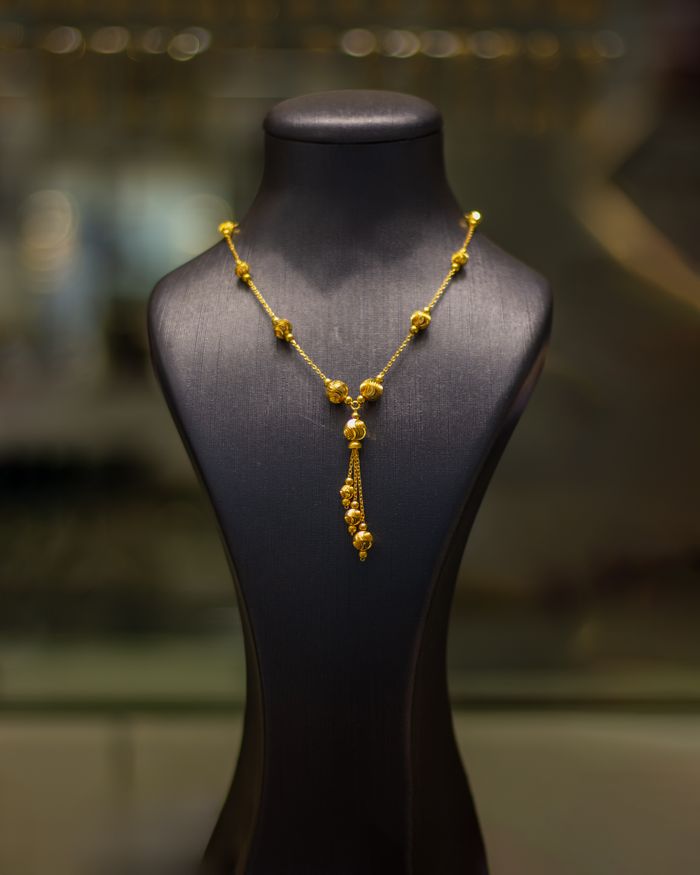 Luxurious gold necklace elegantly displayed on a black mannequin in a jewelry store.